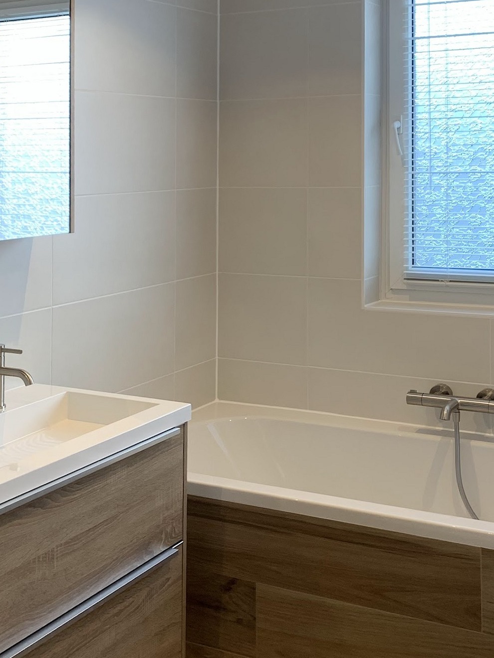 Opgeleverde badkamer met ligbad, houtlook vloer en wastafelmeubel
