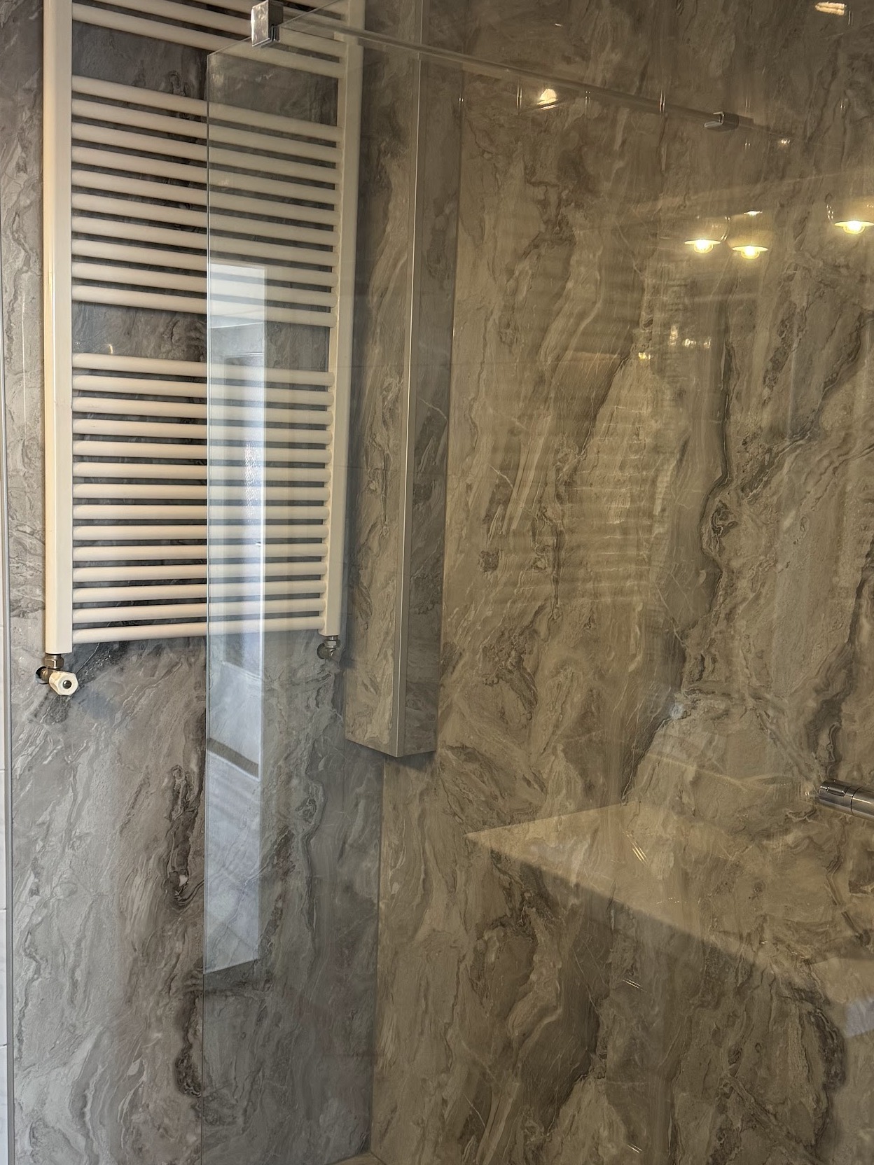 Opgeleverde inloopdouche met steenlook wandpanelen en designradiator