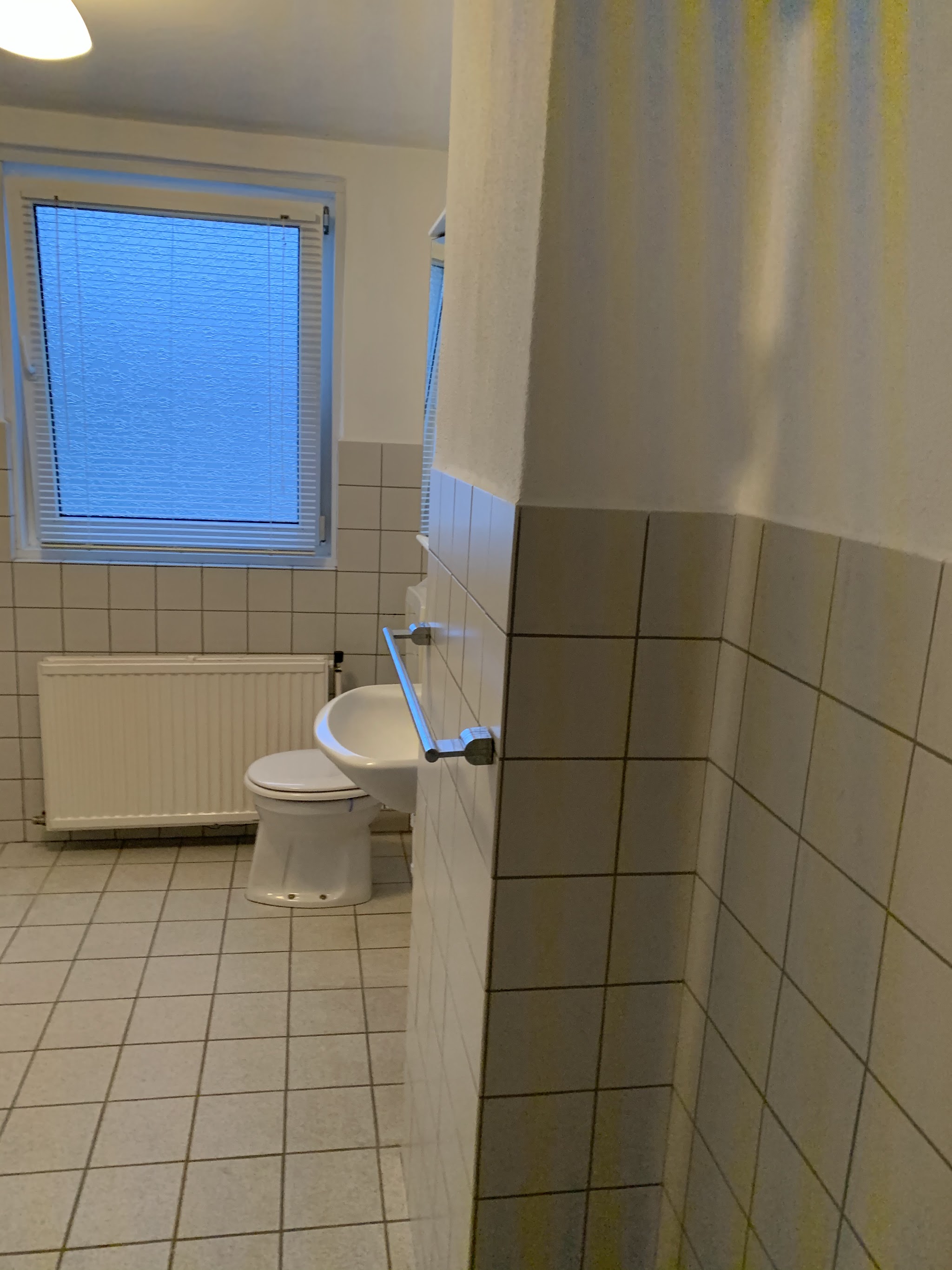 Bestaande badkamer met witte tegels, toilet en bidet