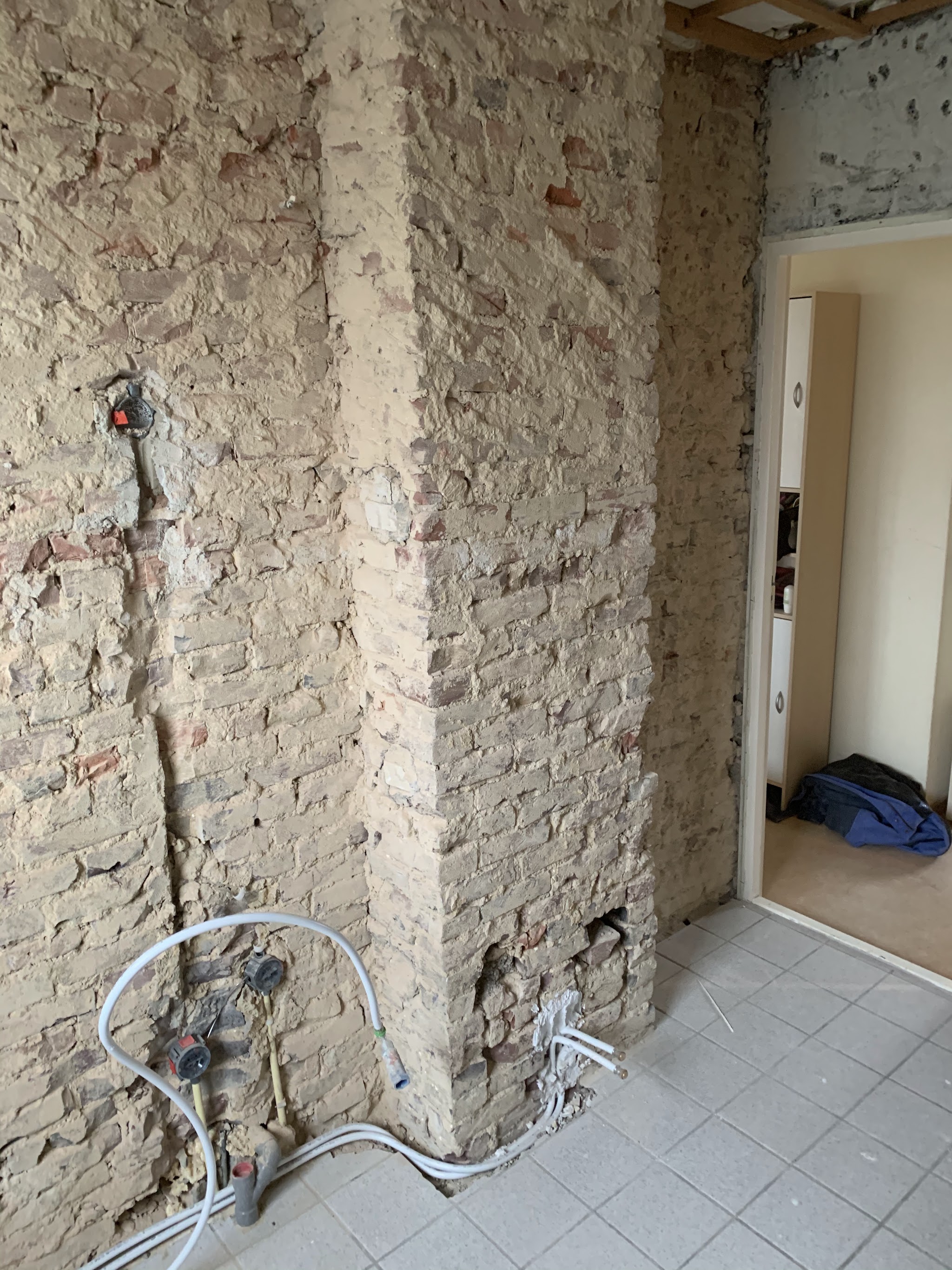 Nieuwe water- en gasleidingen op een gestripte badkamermuur